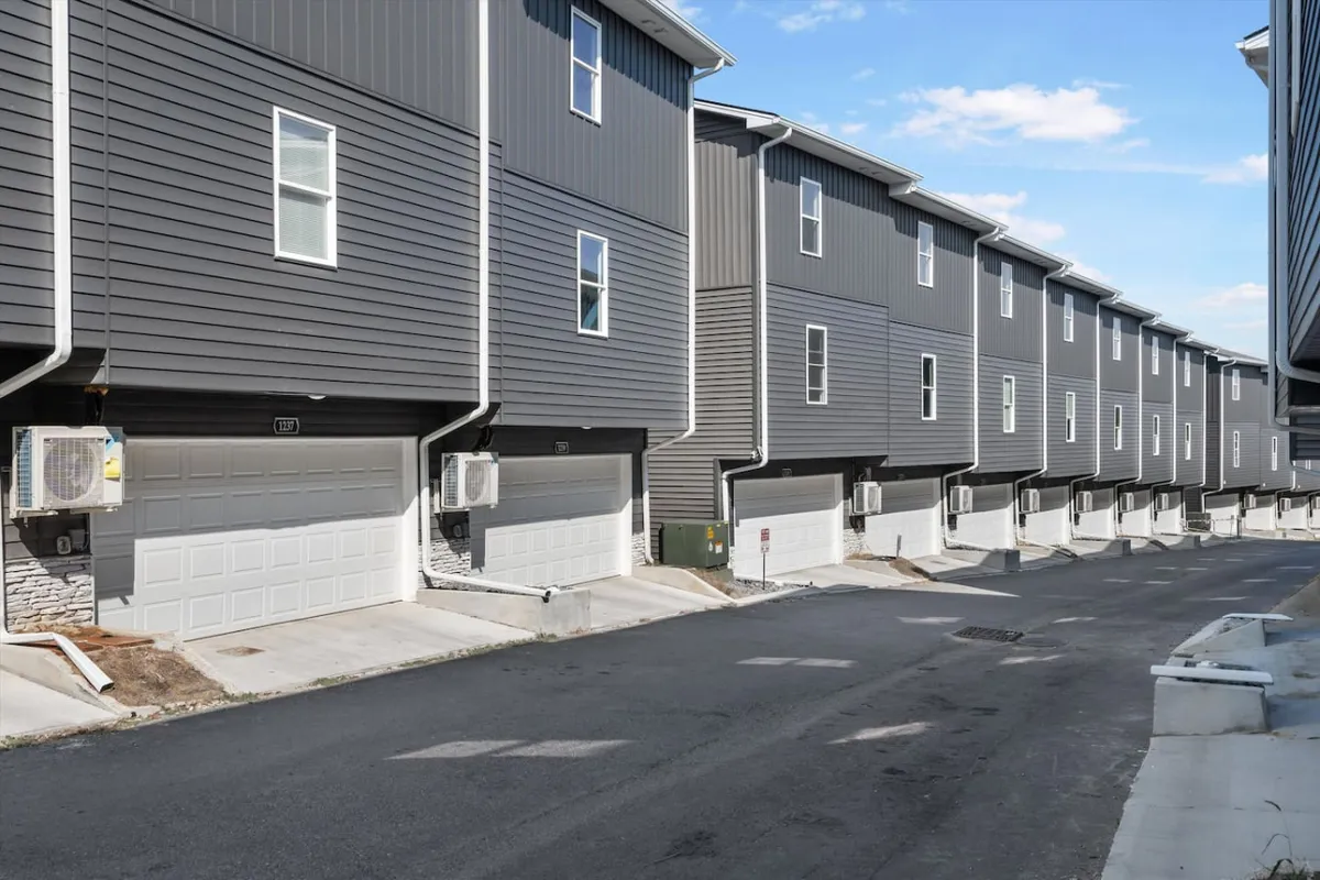 This exterior image highlights a row of townhomes with visible garage doors and windows. The organized and functional look of the buildings emphasizes the availability of private, in-unit garage parking for residents.