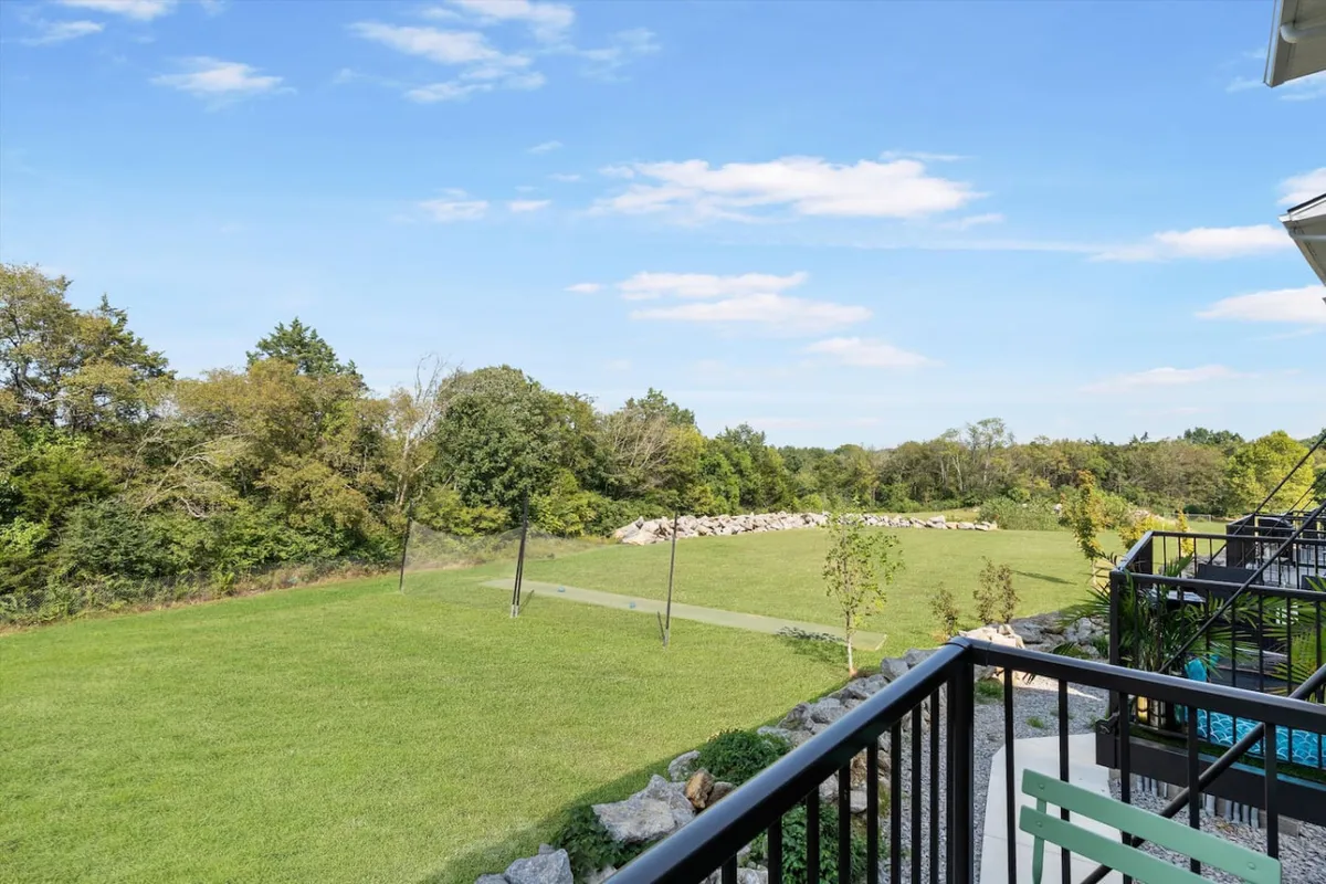 A sweeping view of a lush, expansive green lawn bordered by a distant tree line under a brilliant blue sky. There’s an inviting sense of open space, perfect for outdoor activities like picnicking, jogging, or simply relaxing in nature.