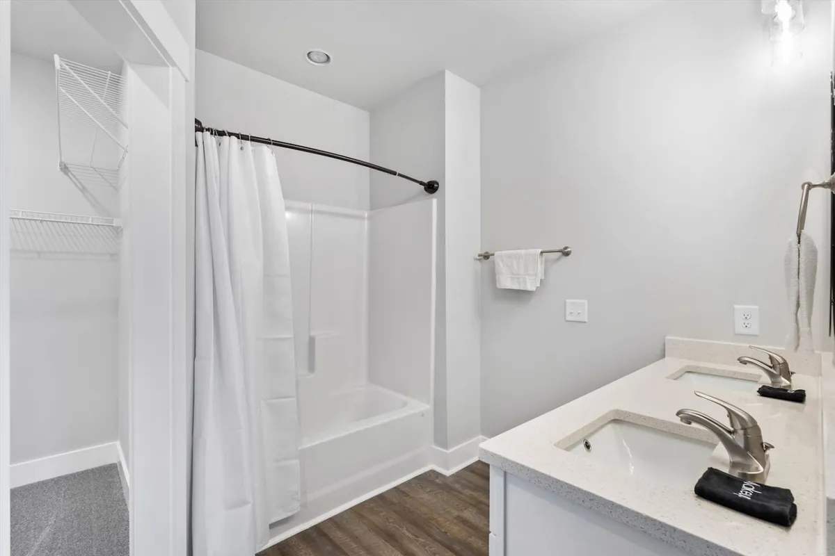 A modern ensuite bathroom with double vanity sinks, a spacious shower area, and contemporary fixtures. The calming and refreshing ambiance is perfect for unwinding after a long day or enjoying a peaceful morning routine.
