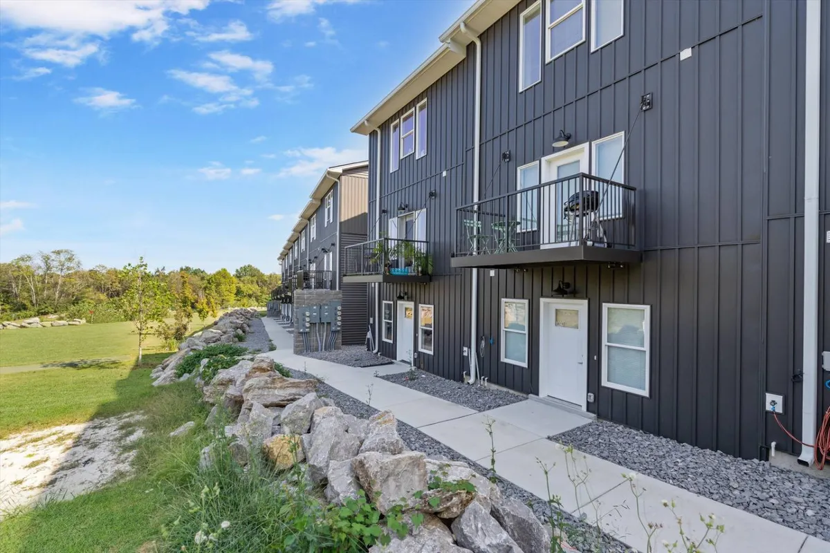 A modern exterior view highlighting the property's fresh architecture, with balconies and a well-maintained rock garden along a welcoming pathway. The scene is bathed in natural light, inviting families or groups to imagine gathering outdoors or heading out for an adventure.