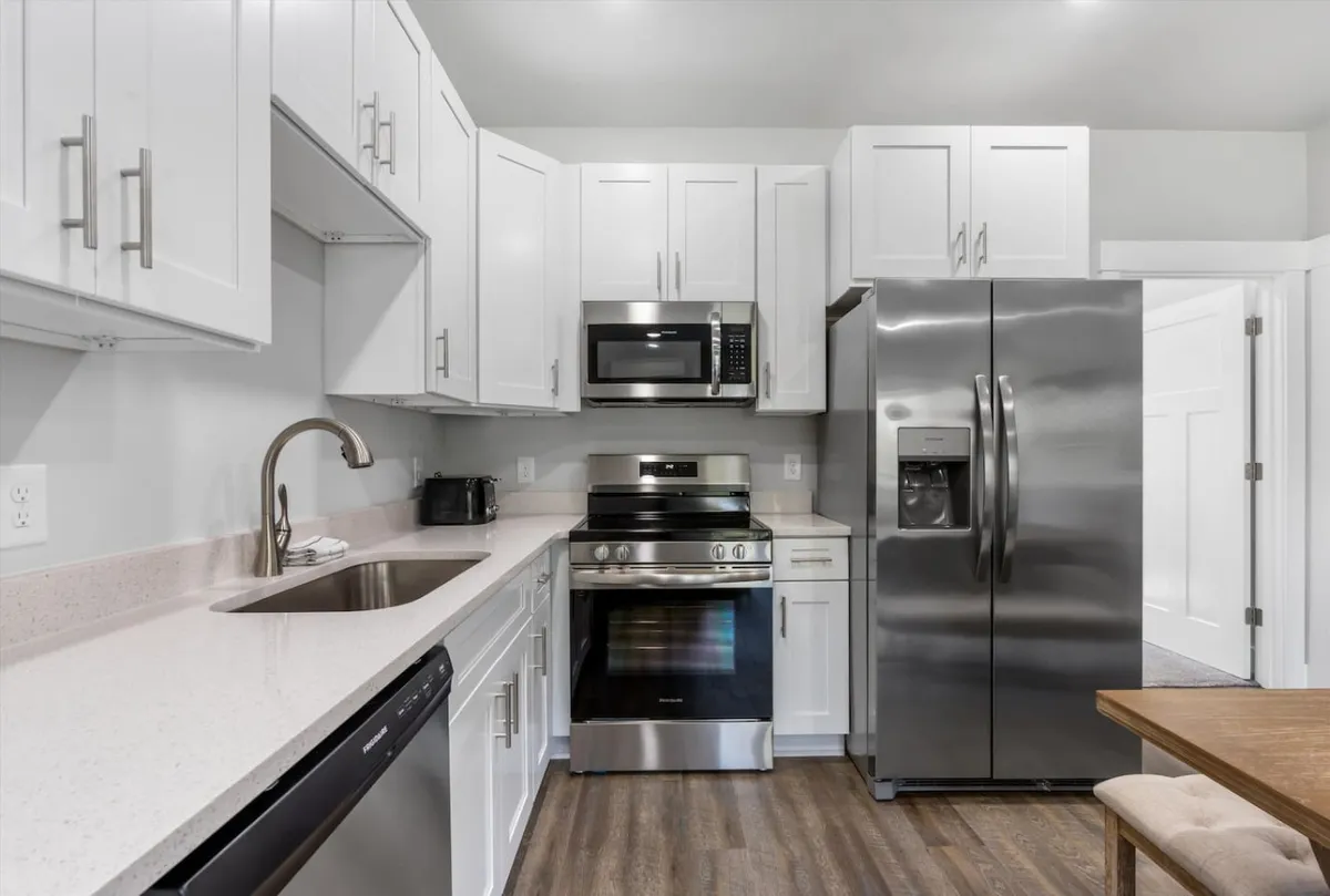 A well-equipped kitchen with stainless steel appliances and white cabinetry, providing a clean, functional, and inviting environment for preparing meals and dining together.