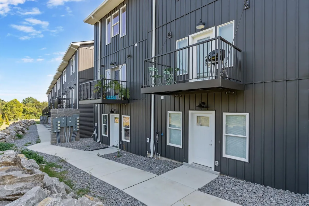 A contemporary balcony setup with comfortable chairs and a well-maintained pathway below, bordered by stylish rock landscaping. The space is ideal for relaxing before setting out, or winding down after exploring Nashville's attractions.